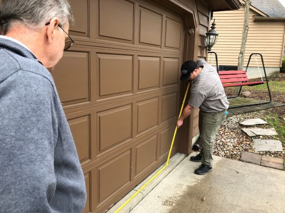 Precision Garage Door Toledo Technician measuring base of garage door as part of garage door maintenance
