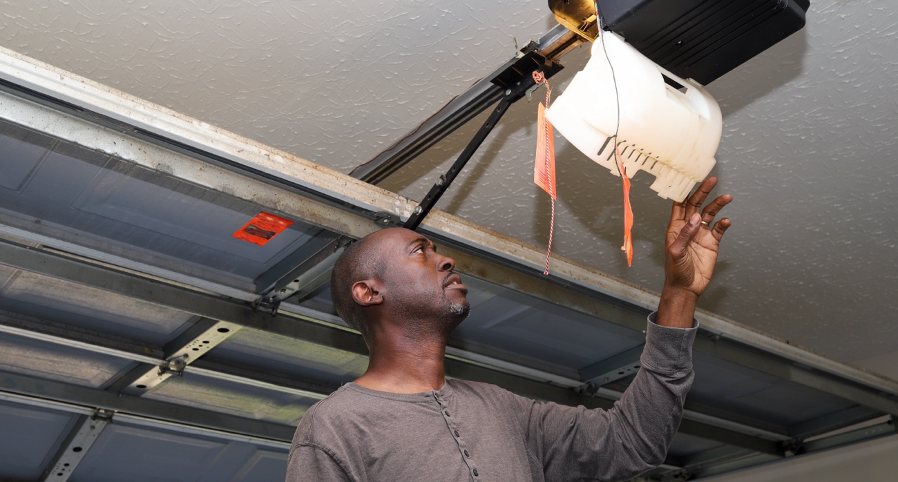 Man looking at interior of garage door opener inside garage. Man looking at interior of garage door opener inside garage.