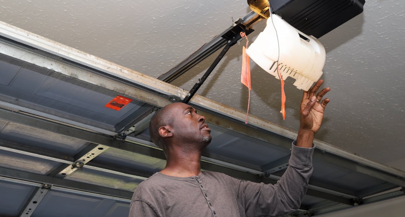 Man looking at interior of garage door opener inside garage.