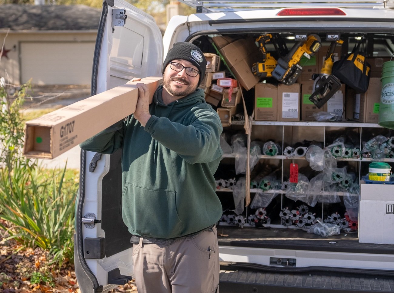 Precision Technician Carrying Garage Door Part from Vehicle