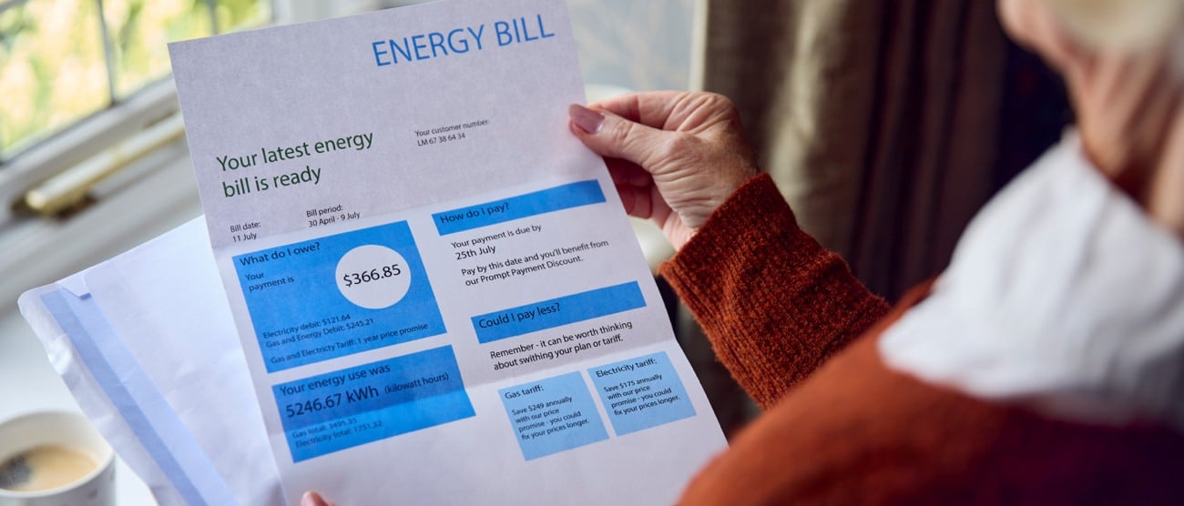 Elderly woman holding raised energy bill