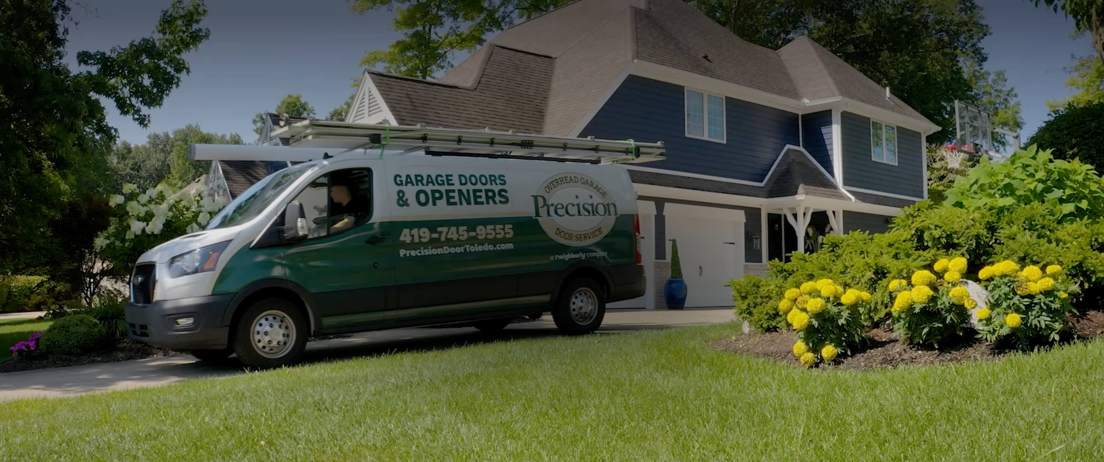 Precision Garage Door Service of Toledo van outside of house with new garage door.